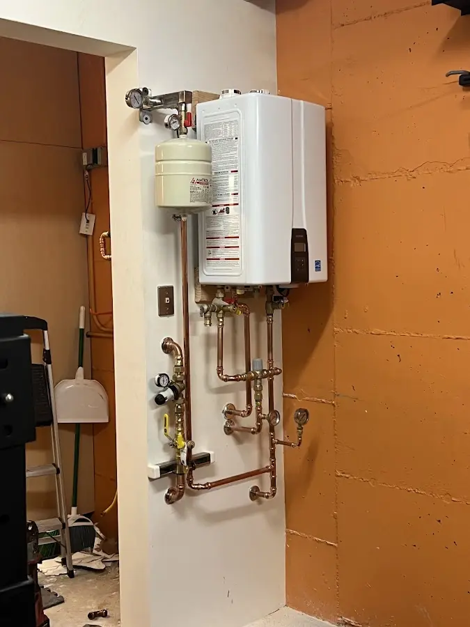 Plumbing technician inspecting water heater connections in Ambridge